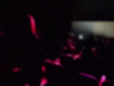 People take their seats in a dark auditorium.