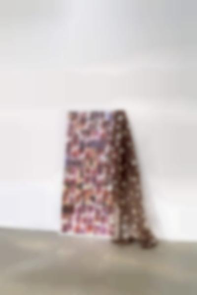 Art installation consisting of several photo prints of anuses glued to a linen canvas, which has been propped against a white wall. A brown nylon textile with silver stars is draped on the right.