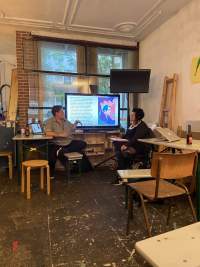 Two people are having a discussion in front of a screen showing an image and some text.