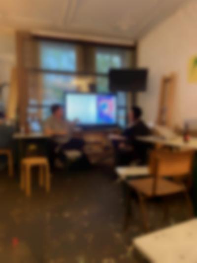 Two people are having a discussion in front of a screen showing an image and some text.