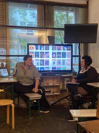 Two people are having a discussion in front of a screen showing several images.