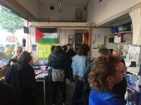 In a small indoor space, a group of people either socialise or look at books.