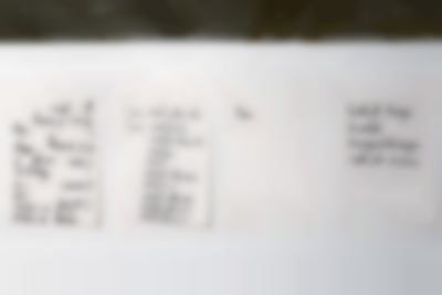 Four white A4 sheets, with Dutch words handwritten in black ink, are stuck to a wall.