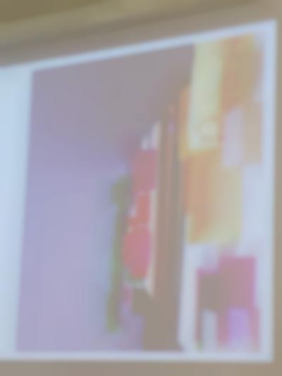 A slide with an image is being projected. The image is a photograph of a shelf of books annotated with colourful sticky notes.