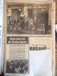 Collage made from a newspaper page. Half of the page is occupied by a photograph depicting a group of people standing in front of a storefront. At the bottom half, there's an article with a photo and a missing chunk, on top of which there's a cut out from a different page, which only partially occupies the missing space.