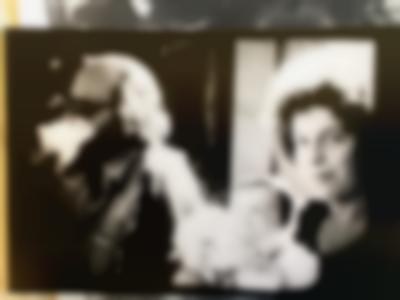 A feminine-presenting person holds a baby and faces the camera. To the left, a masculine-presenting person, wearing sunglasses, looks away.