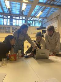 Students gather around the screen in a listening session with ekphrastic texts from *Black Revelry: In Honor of 'The Sugar Shack'* by Derrais Carter (2021). If I Can't Dance, Amsterdam, 2023.