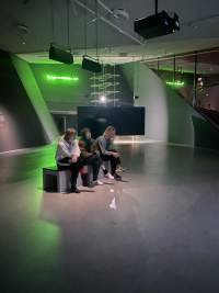 Students sit inside the exhibition *Feed me. Cheat me. Eat me.* by Janis Rafa. EYE Filmmuseum, Amsterdam, 2023.