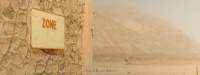A worn-out sign, with the word Zone still visible, hangs on a building. In the background, there is a hill in an arid area. A subtitle reads: 