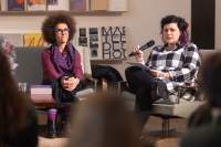 Two people sit next to each other on a stage. Megan speaks into the microphone. At the front, slightly blurred, three people face the stage.