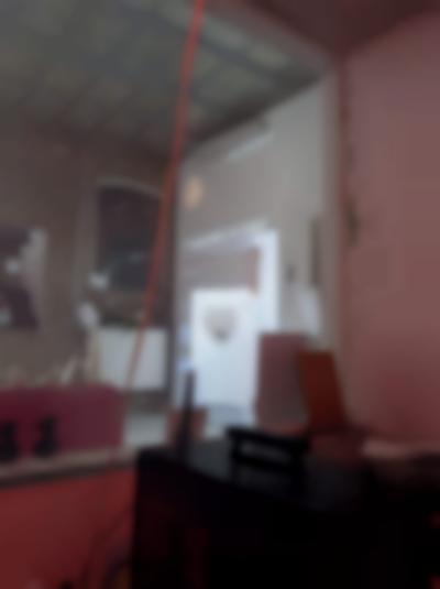 On the other side of a glass, an image is being projected in one of the walls of a gallery space. Above the image with a drawing of a face, text white reads: 