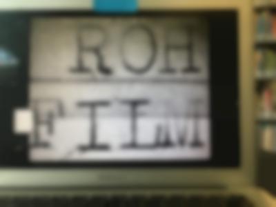 A film still appears in a grey laptop screen. The black and white still reads 