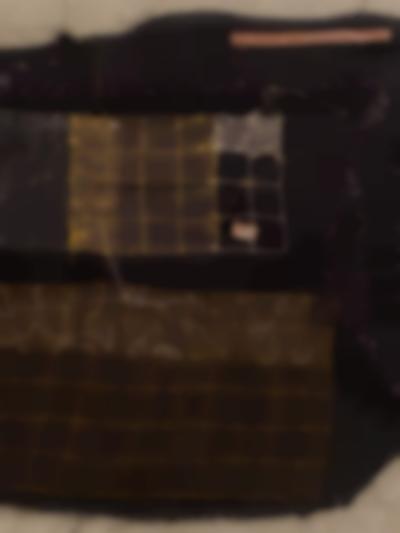 Section of a piece of dark fabric with stitches in white, brown and yellow. These stitches appear in different shapes and form patterns.