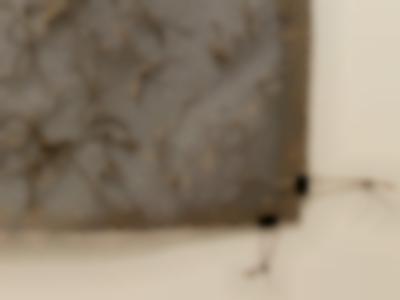 Close up section of a large rectangular piece of fabric hung on the wall. There is some texture to it, created with stitching.