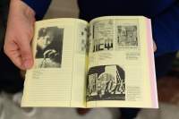 A book is held open, showing a spread with yellow pages and four different images with descriptions. In the most visible them, a person uses a compass.