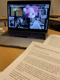 Open laptop computer, showing a desktop with several open image files. Two text printouts are laying next to the computer.