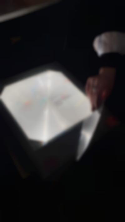 Handwritten notes, in several colours, have been written in a transparency sheet and left on top of an overhead projector's stage. A hand is partially visible, holding the corner of the sheet.